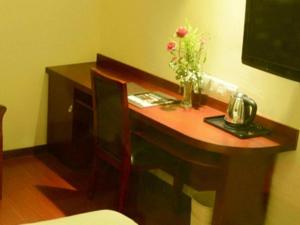 a wooden desk with a vase of flowers on it at GreenTree Inn Shanghai Waigaoqiao Free Trade Zone Express Hotel in Shanghai