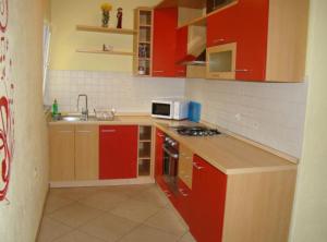 a small kitchen with red cabinets and a microwave at Apartments Snježana in Sali