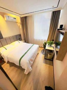 a bedroom with a large white bed and a table at GreenTree Inn Langfang Sanhe South Yingbin Road Express Hotel in Sanhe
