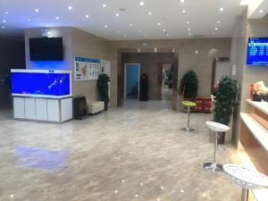 Wensuにある7 Days Inn Aksu Airportの建物内のスツールとテレビのあるロビー