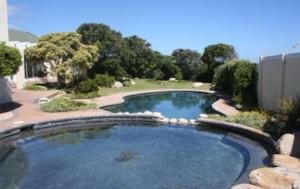 a large swimming pool in a yard with a landscaping at Whale Rock 54 in Hermanus