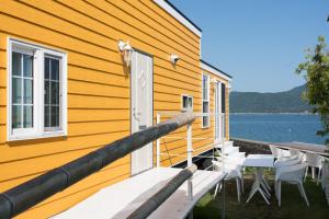 a yellow house with a table and chairs on a dock at 宮島リゾート Hauol'i in Hatsukaichi