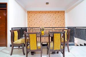 a dining room table with chairs and a vase of flowers at Hotel O Jawara Guest House Syariah in Bandung