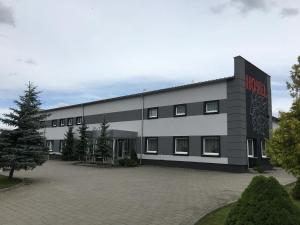 un gran edificio blanco con un letrero rojo. en Canpol, en Czluchów