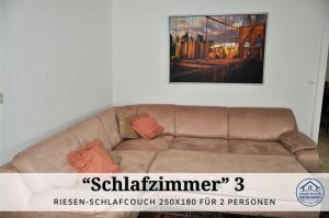 eine braune Couch in einem Wohnzimmer mit einem Gemälde an der Wand in der Unterkunft Apartment Karin - Modern ausgestattet und ideal für Gruppen bis 6 Personen und Hund, egal ob Familie, Kollegen oder Freunde, 85qm mit Terasse und eigenem Stellplatz in Riegelsberg