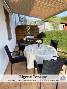 ein Tisch auf einer Terrasse mit Stühlen und einem Grill in der Unterkunft Apartment Karin - Modern ausgestattet und ideal für Gruppen bis 6 Personen und Hund, egal ob Familie, Kollegen oder Freunde, 85qm mit Terasse und eigenem Stellplatz in Riegelsberg