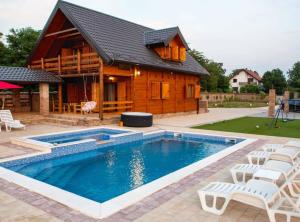 a house with a swimming pool in front of a house at Wooden House Vučedol in Vukovar