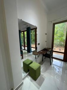sala de estar con mesa y 2 taburetes verdes en Sigiriya Hotel and Resort, en Sigiriya