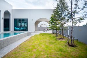 a house with a tree in the middle of a yard at Triple P พูลวิลล่า ชะอำ in Ban Bo Prakhon