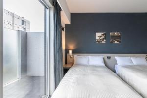 Un dormitorio con dos camas y una gran ventana. en Hotel Vista Kumamoto Airport, en Ozu