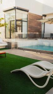 a white chair sitting on the grass next to a pool at Hummingbird Rak in Ras al Khaimah