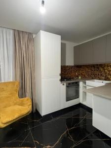 a kitchen with white cabinets and a yellow chair in it at GZP Residence Lugoj 16 in Lugoj
