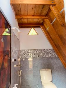 a bathroom with a toilet and a wooden ceiling at Angry Birds Tree house new cabana in Habarana