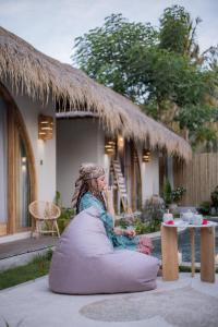 Eine Frau sitzt auf einem Sitzsack vor einem Haus in der Unterkunft Villa Nyantara in Gili Air