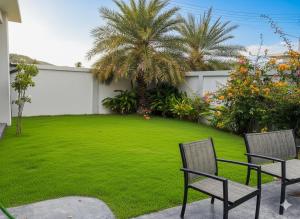 einen Garten mit zwei Stühlen und einer grünen Wiese in der Unterkunft Modern pool villa nature and beach Pak Nam Pran - hua hin in Ban Nong Sua + 9 Fotos
