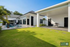 ein Hinterhof eines Hauses mit einem grünen Rasen in der Unterkunft Modern pool villa nature and beach Pak Nam Pran - hua hin in Ban Nong Sua