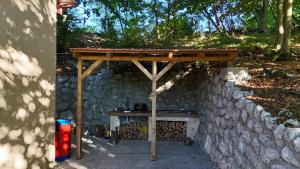 a wooden table with a wooden roof on a stone wall at Vikendica Silenzio in Cetinje