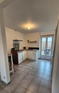 een keuken met witte apparatuur en een grote tegelvloer bij Studio La Pause d'un Soir in Roye
