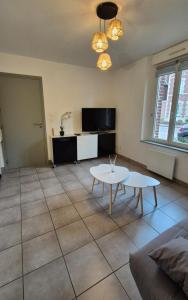 een woonkamer met een tafel en een tv bij Studio La Pause d'un Soir in Roye +5 foto's