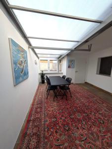 Zimmer mit einem Tisch und Stühlen auf einem roten Teppich in der Unterkunft Modern habitable gallery, centrally located in Hirschaid in Hirschaid