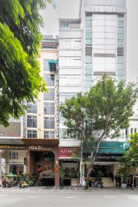 un grand bâtiment blanc avec un arbre devant lui dans l'établissement A25 Hotel - 25 Trương Định, à Hô-Chi-Minh-Ville