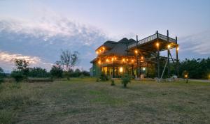 a house with lights on it in a field at Enshama Game Lodge and Campsite in Katunguru