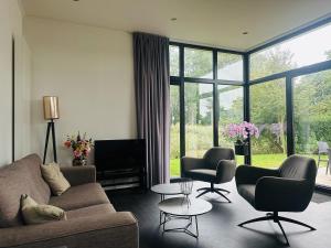 a living room with a couch and two chairs at Stylish chalet in nature near Amsterdam in Halfweg