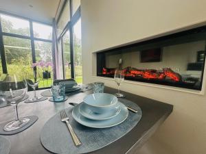 a table with plates and wine glasses and a fireplace at Stylish chalet in nature near Amsterdam in Halfweg