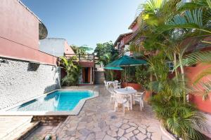 eine Terrasse mit einem Tisch, einem Sonnenschirm und einem Pool in der Unterkunft Meu Sonho Búzios in Búzios