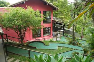 a red house with a pool in front of it at Pousada Golf Village in Itaipava