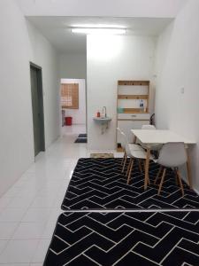 a dining room with a table and chairs on a rug at Alfateh Homestay in Sungai Petani