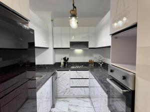 New cairoرويال شقة بالتجمع الخامس امتداد الجامعة الامريكية的厨房配有白色橱柜和黑色台面