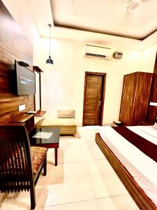 a bedroom with a bed and a desk and a tv at Hotel WoodCrest Chandigarh Zirakpur in Chandīgarh