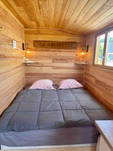 a bed in the corner of a tiny house at La Galipette, charmant chalet en Champagne in Fleury-la-Rivière