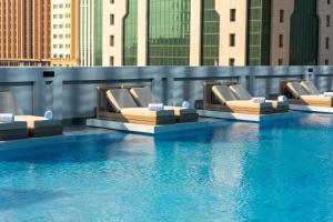 a row of chairs sitting next to a swimming pool at Thirty Five Westbay Luxury Apartments in Doha