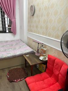 Cette chambre comprend une chaise rouge et une table. dans l'établissement TayHo Rose202 Homestay, à Hanoï