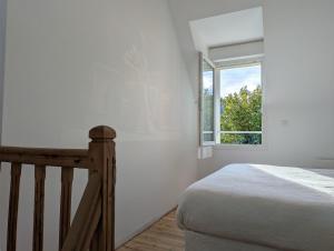 ein weißes Schlafzimmer mit einem Bett und einem Fenster in der Unterkunft Escale Lomy en bord de mer avec Sauna et Jacuzzi in Pléneuf-Val-André