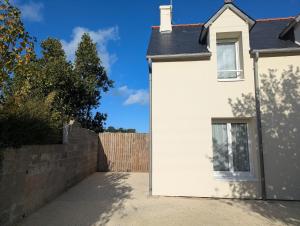 ein weißes Haus mit einem Zaun davor in der Unterkunft Escale Lomy en bord de mer avec Sauna et Jacuzzi in Pléneuf-Val-André