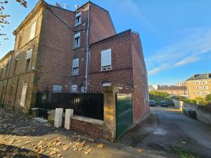 an old brick building with a green door on a street at Budget Studio avec Parking in Charleville-Mézières +5 photos