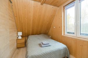 a small bedroom with a bed and a window at Całoroczny, drewniany domek przy lesie in Prażmów
