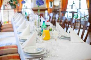 a long white table with plates and glasses on it at Pokoje De Luxe Figaro in Płock