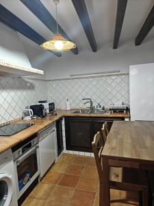 eine Küche mit einem Tisch, einer Spüle und einer Theke in der Unterkunft Casona Arquillo del Judío in Toledo