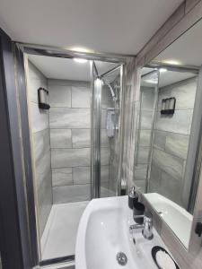 une salle de bain avec un lavabo blanc et une douche dans l'établissement The Orange Outpost - Modern Studio Near Alhambra, à Bradford