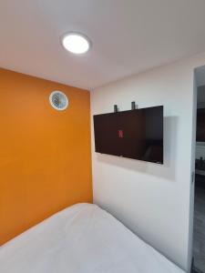 une chambre avec une télévision à écran plat au mur dans l'établissement The Orange Outpost - Modern Studio Near Alhambra, à Bradford