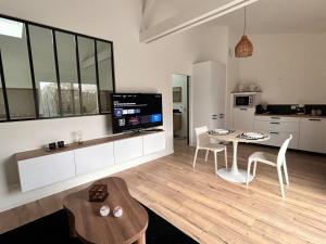 a living room with a table and chairs and a kitchen at Un toit pour 2 in Le May-sur-Èvre +5 photos