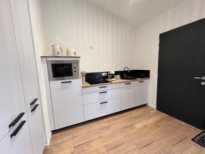 Una cocina blanca con fregadero y microondas. en Un toit pour 2, en Le May-sur-Èvre