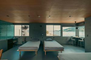 a room with two beds and a kitchen with windows at TATARA FACTORY stay in Imabari