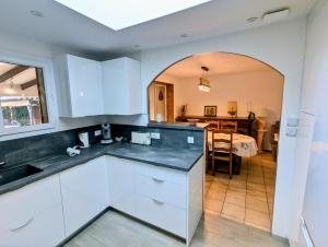 een keuken met witte kasten en een eetkamer bij Maison 3 étoiles climatisée, jardin, parking, proche centre et thermes in Dax +23 foto's