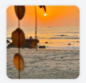 a sunset on the beach with a person in the ocean at Doman Doman Eco Lodge in Gunjur