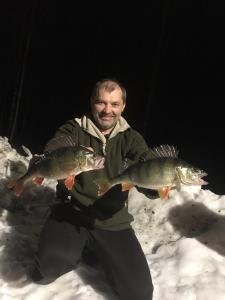 MelkoniemiTarula Holiday Home的一名男子在雪地里抱着一对鱼